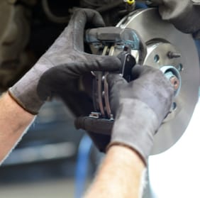 Close-up of mechanic repairing a vehicle's brakes in a garage