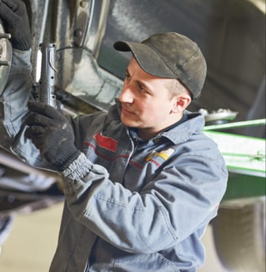 Auto repair technician working on suspension repair in garage