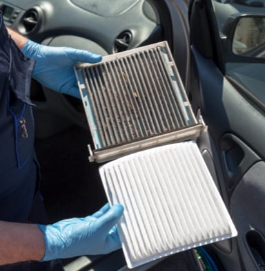 Mechanic holding a dirty and a clean auto air filter in each hand
