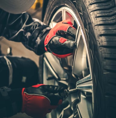 Mechanic in a garage with red and black gloves rotating a tire