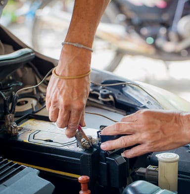 Mechanic's hands replacing a car battery