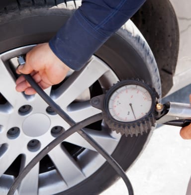 Person checking their tire pressure using a pressure gauge