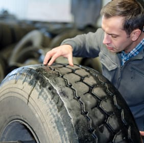 Man closely observing the treads of a dusty tire