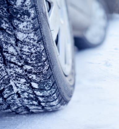Close-up of a car's winter tires outside driving in the snow